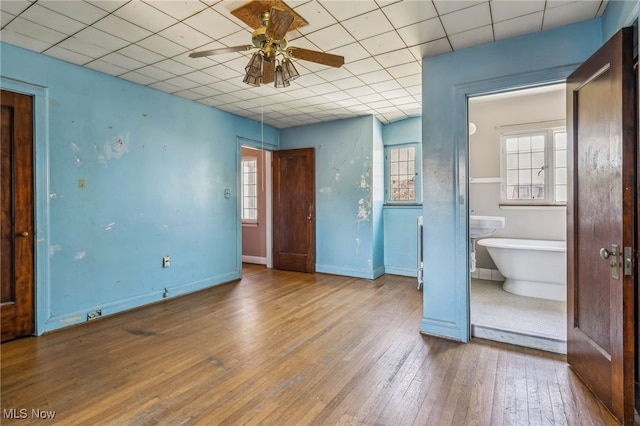 unfurnished bedroom with hardwood / wood-style flooring, baseboards, and a drop ceiling