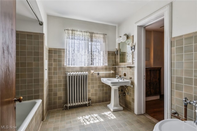 full bath featuring a sink, a relaxing tiled tub, tile walls, radiator, and tile patterned flooring