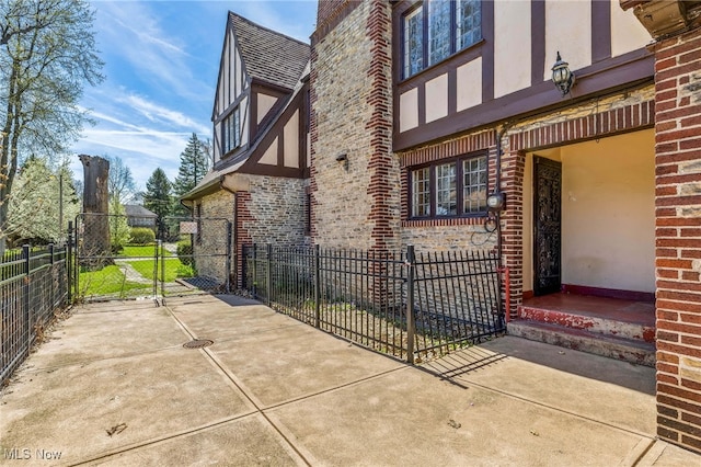 view of property exterior with brick siding, a gate, stucco siding, and fence