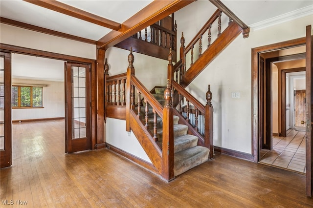 staircase featuring hardwood / wood-style floors, baseboards, and crown molding