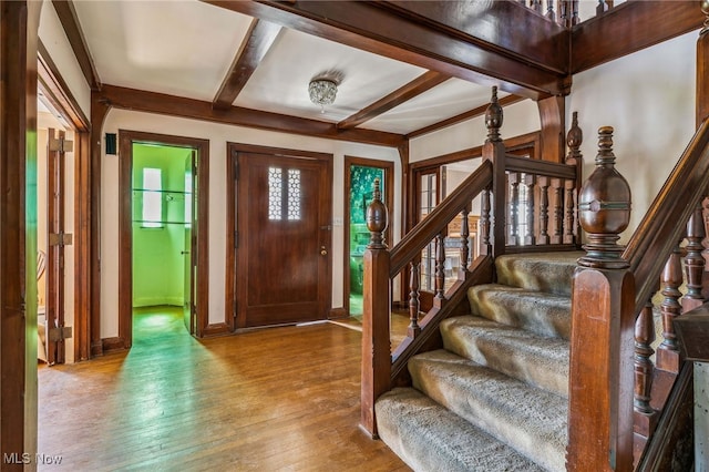 foyer with stairway, beam ceiling, baseboards, and wood finished floors