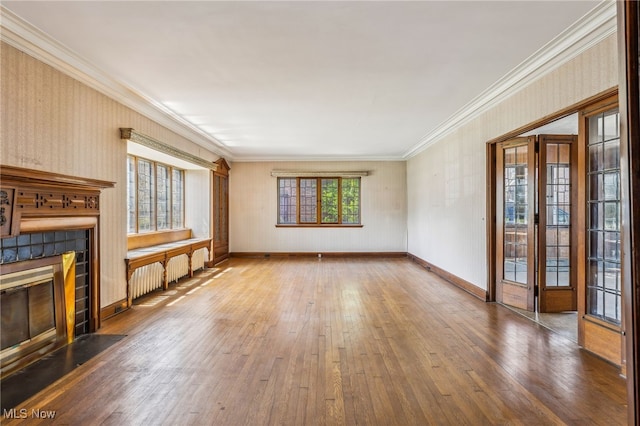unfurnished living room with a fireplace with flush hearth, wood-type flooring, crown molding, and baseboards