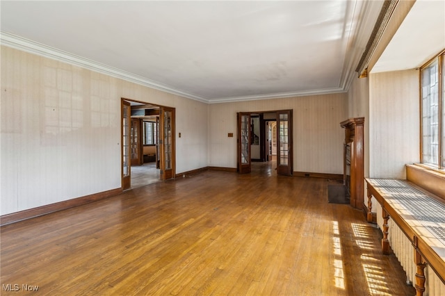 spare room with hardwood / wood-style flooring, baseboards, and crown molding