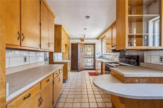 kitchen with under cabinet range hood, stainless steel appliances, light countertops, light tile patterned floors, and decorative backsplash