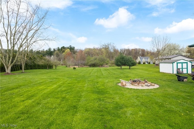 view of yard featuring a fire pit, an outbuilding, and a storage shed