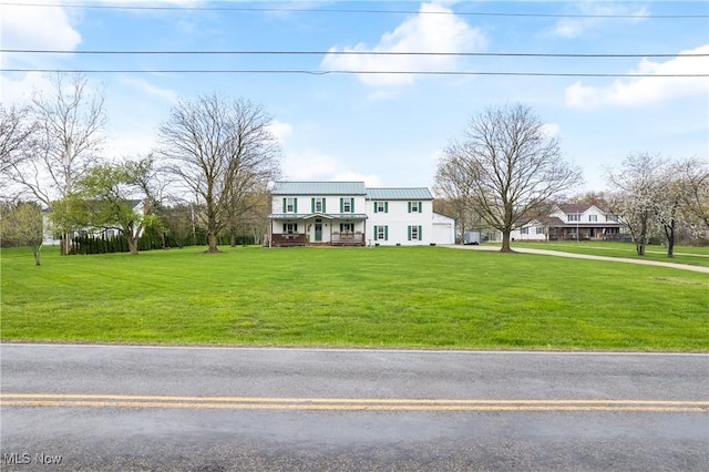 colonial home featuring metal roof, a garage, a front yard, and covered porch