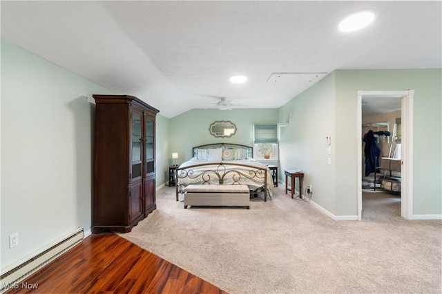 bedroom with vaulted ceiling, wood finished floors, a baseboard heating unit, carpet, and baseboards