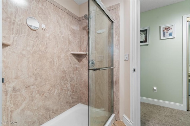 bathroom featuring a shower with shower door and baseboards