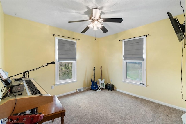 unfurnished office featuring carpet flooring, a healthy amount of sunlight, baseboards, visible vents, and a ceiling fan