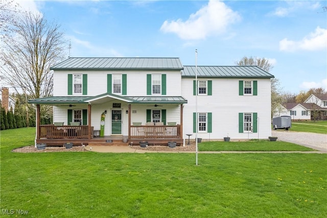 view of front facade featuring ceiling fan, a standing seam roof, a porch, a front yard, and metal roof