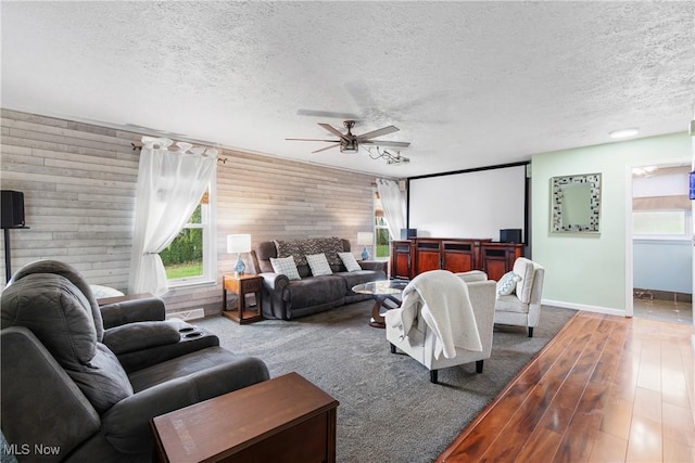 interior space with wood walls, a wealth of natural light, a textured ceiling, and ceiling fan