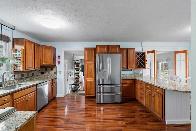 kitchen with dark wood-type flooring, brown cabinetry, appliances with stainless steel finishes, and a sink