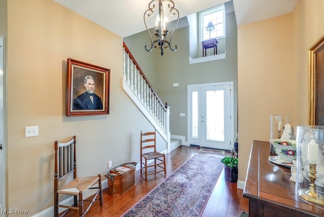 foyer entrance featuring a wealth of natural light, a notable chandelier, stairs, and dark wood-style floors