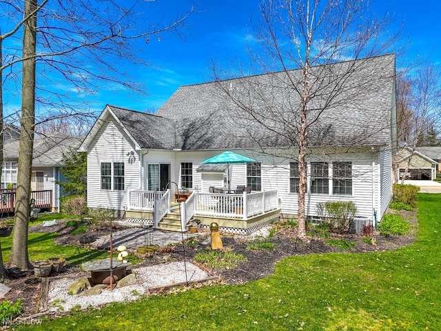view of front facade with cooling unit, a shingled roof, a front yard, and a deck