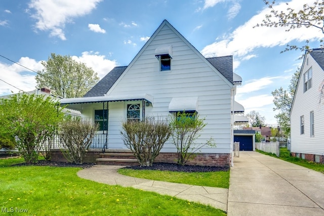 bungalow-style home with an outbuilding, covered porch, a shingled roof, and a front yard