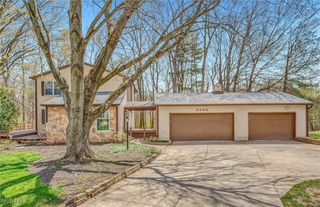view of front of house with concrete driveway, stone siding, a chimney, and a garage