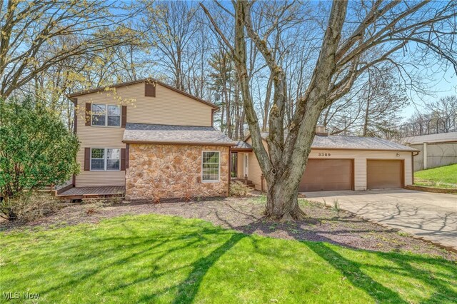 view of front of house with concrete driveway, an attached garage, stone siding, and a front yard