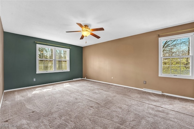 empty room featuring plenty of natural light, visible vents, a ceiling fan, and baseboards
