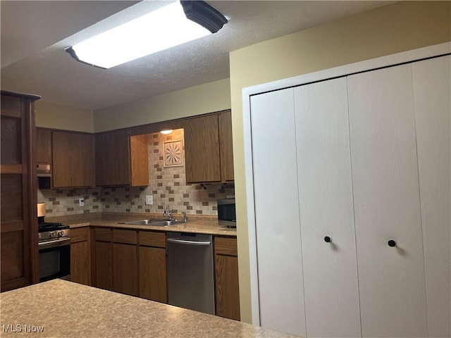 kitchen with a sink, appliances with stainless steel finishes, tasteful backsplash, and light countertops