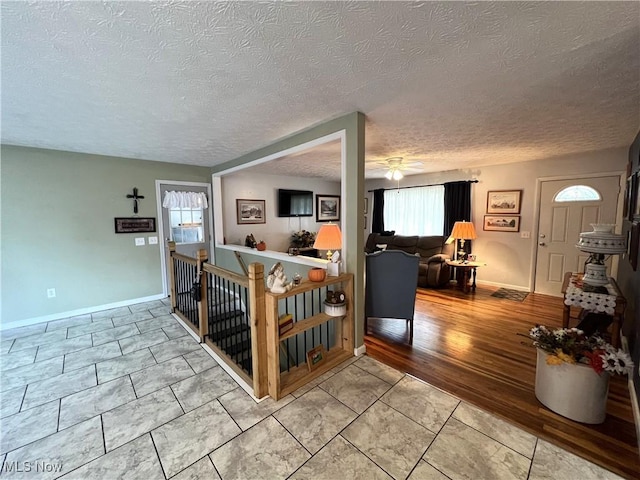 interior space featuring a textured ceiling, baseboards, and ceiling fan