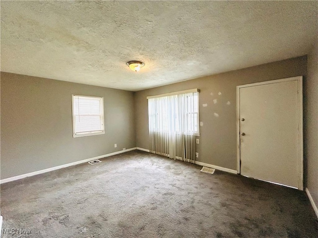 spare room with baseboards, visible vents, a textured ceiling, and carpet flooring