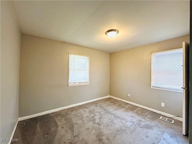 spare room with carpet floors, visible vents, and baseboards