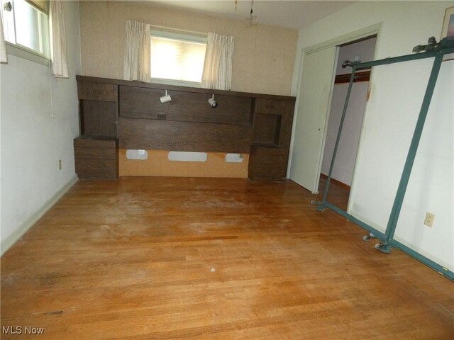 403 Sandy Dr, Cambridge, OH 43725 - unfurnished bedroom with multiple windows, light wood-style floors, a closet, and a barn door