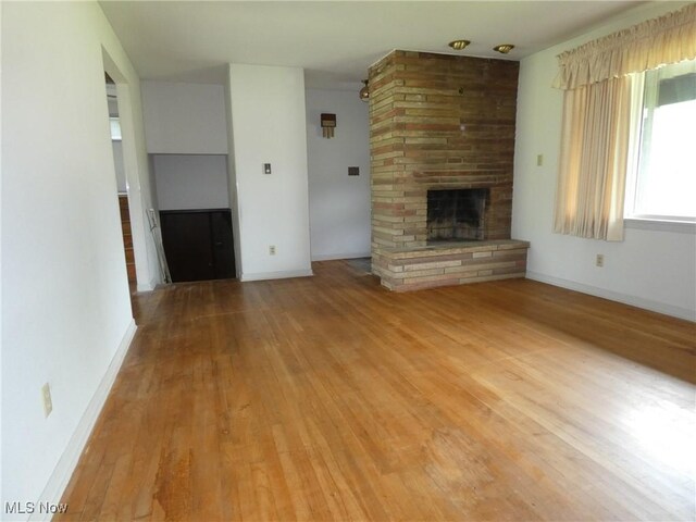 403 Sandy Dr, Cambridge, OH 43725 - unfurnished living room featuring a large fireplace, light wood finished floors, and baseboards