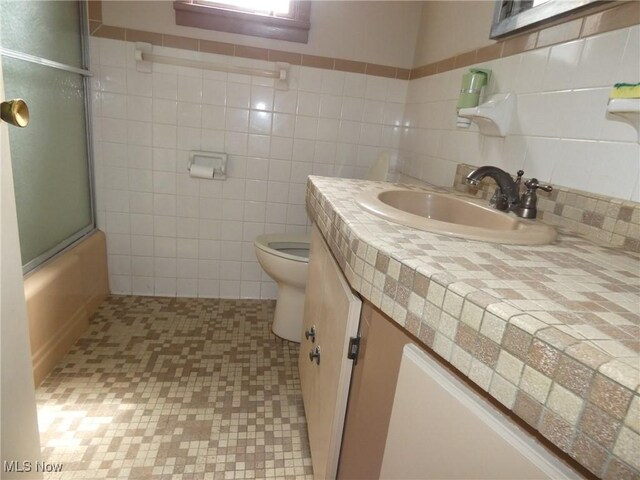 403 Sandy Dr, Cambridge, OH 43725 - bathroom featuring vanity, toilet, combined bath / shower with glass door, tile walls, and tile patterned flooring