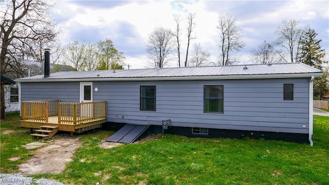 back of property with a wooden deck, a yard, and metal roof