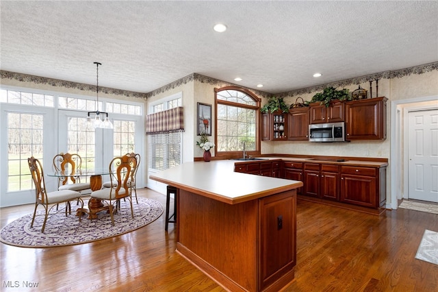 kitchen featuring stainless steel microwave, a textured ceiling, black electric stovetop, and a sink
