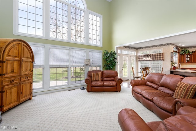 living area with a high ceiling, carpet flooring, and a notable chandelier