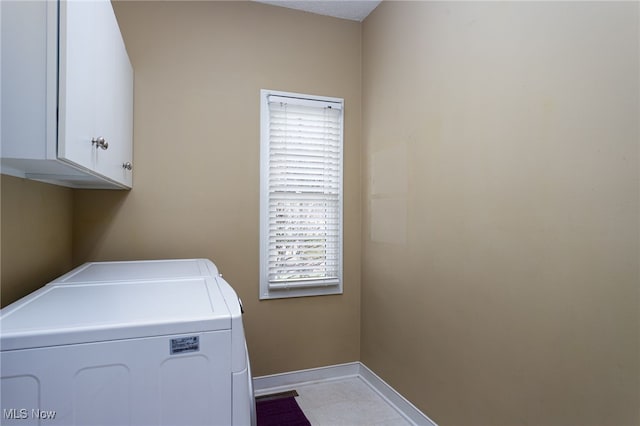 clothes washing area featuring cabinet space, washing machine and clothes dryer, and baseboards