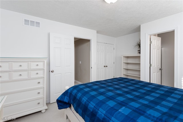 bedroom with light carpet, visible vents, a textured ceiling, and a closet