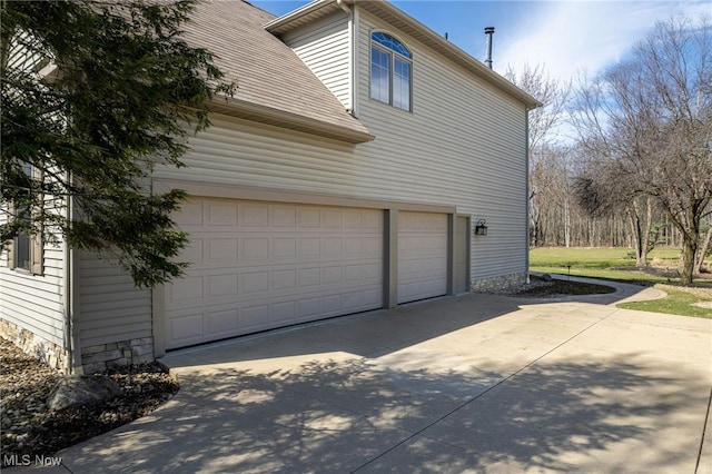 view of side of property with driveway, a shingled roof, and a garage