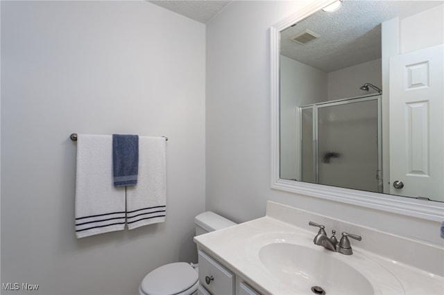 full bath with visible vents, toilet, vanity, a textured ceiling, and a stall shower