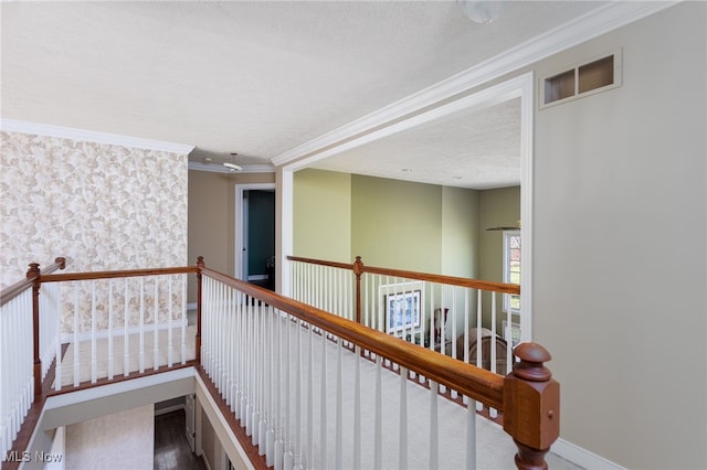 hallway featuring a textured ceiling, visible vents, baseboards, and an upstairs landing