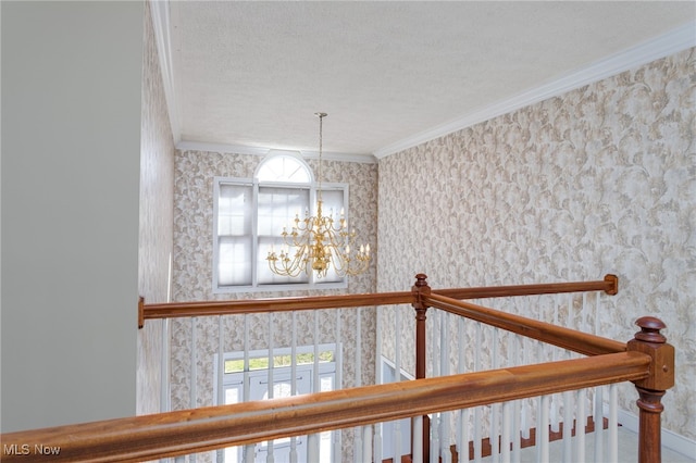 interior space with a chandelier, a wealth of natural light, a textured ceiling, and ornamental molding