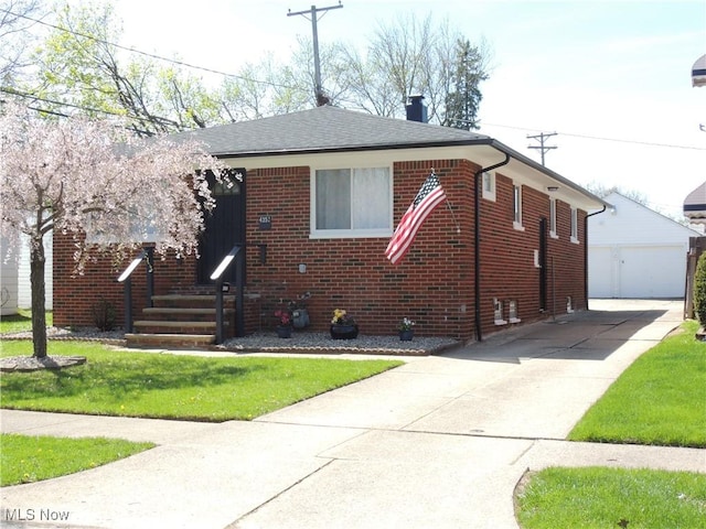 view of front of home featuring a front lawn, a chimney, brick siding, and a garage