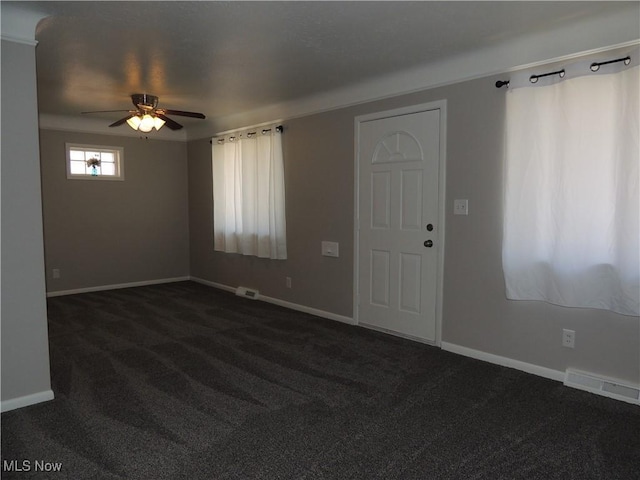 interior space with dark carpet, ceiling fan, baseboards, and visible vents