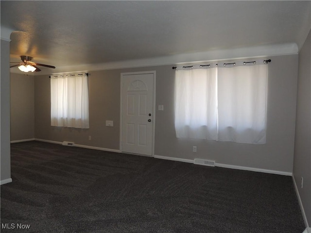 unfurnished living room with dark carpet, baseboards, a ceiling fan, and visible vents