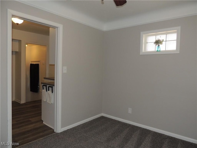unfurnished room featuring dark carpet, baseboards, and ceiling fan