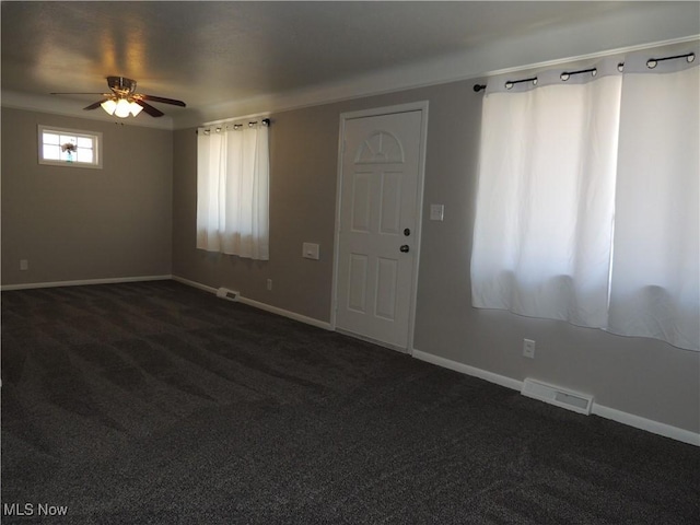 spare room with baseboards, visible vents, dark carpet, and ceiling fan