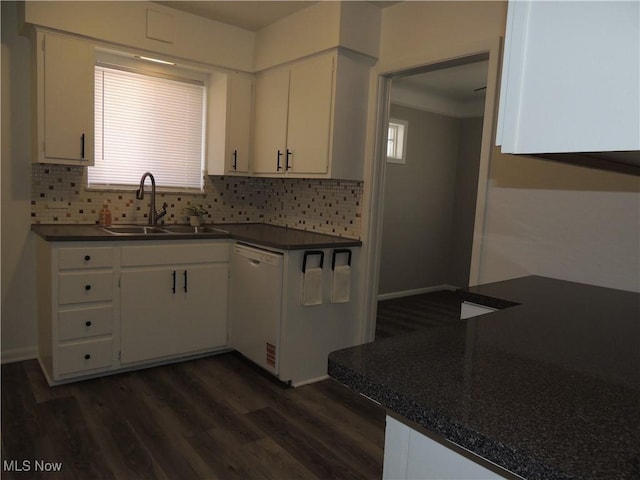 kitchen featuring dark countertops, white dishwasher, a sink, and backsplash