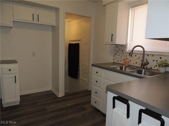 kitchen featuring a sink, dark wood-style flooring, baseboards, tasteful backsplash, and white cabinetry