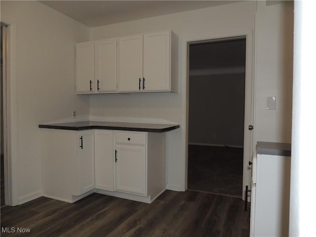 kitchen featuring dark countertops, baseboards, dark wood-style floors, and white cabinetry