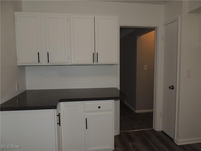 kitchen featuring dark wood finished floors, dark countertops, baseboards, and white cabinetry