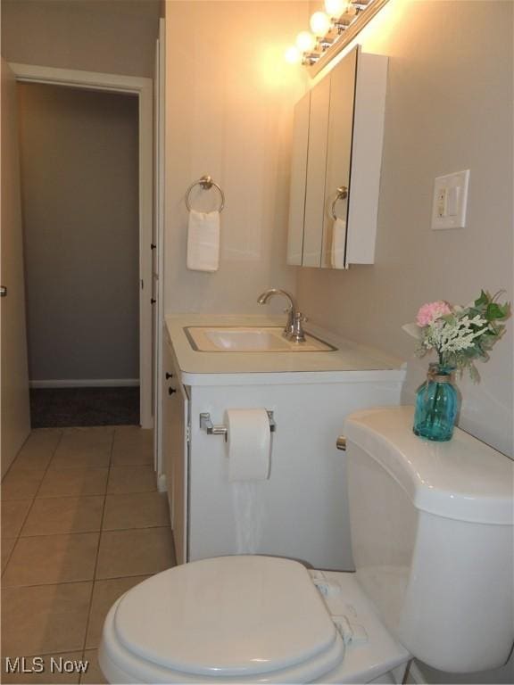 half bathroom with vanity, toilet, and tile patterned flooring