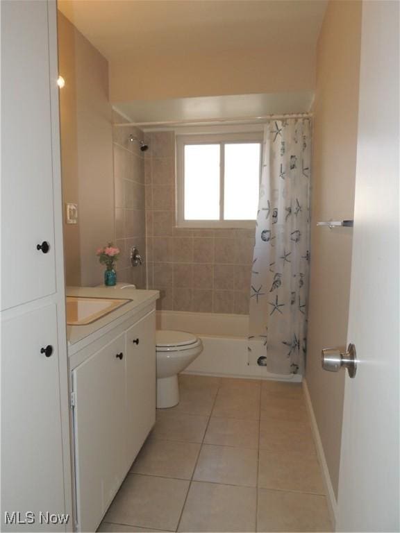 bathroom with tile patterned floors, vanity, toilet, baseboards, and shower / bath combination with curtain