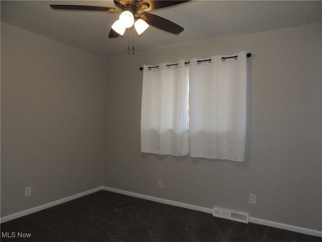 spare room with ceiling fan, baseboards, dark colored carpet, and visible vents
